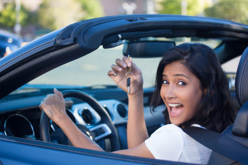 Closeup portrait young cheerful joyful smiling gorgeous woman holding up keys to her first new sports car. Customer satisfaction
